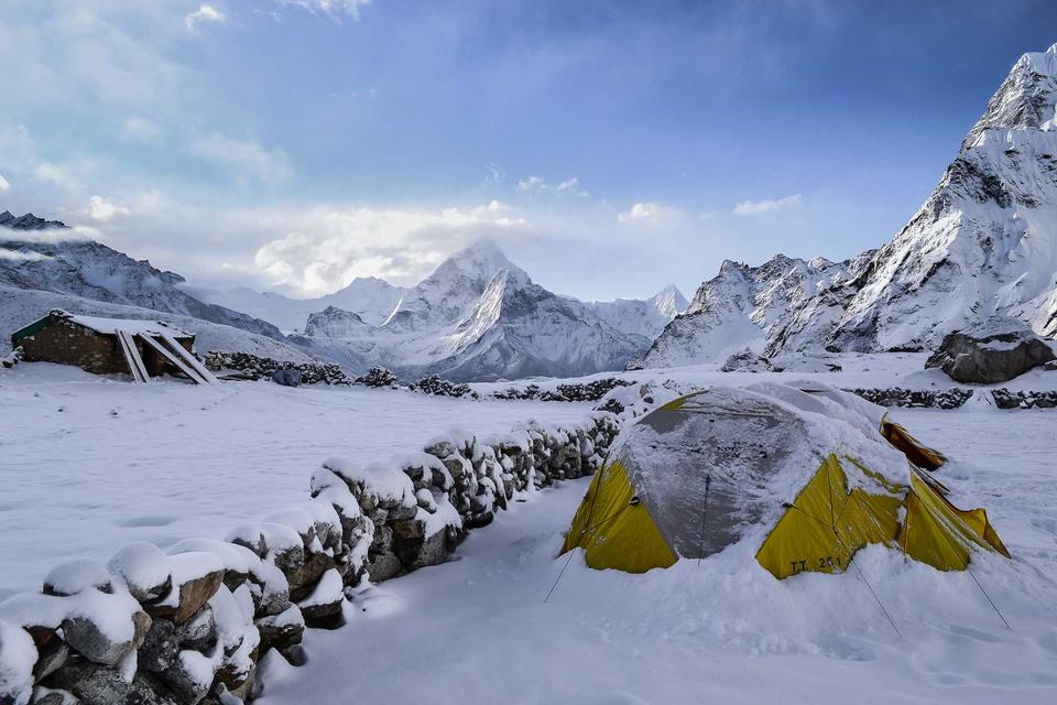 Snowy mountain valley with yellow tents